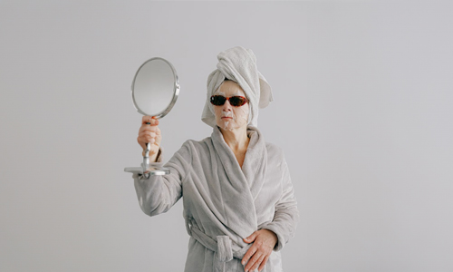 Woman with sheet mask and coolers with mirror in hand 