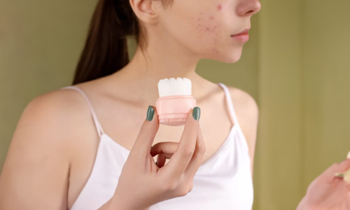 Woman with face cleansing brush